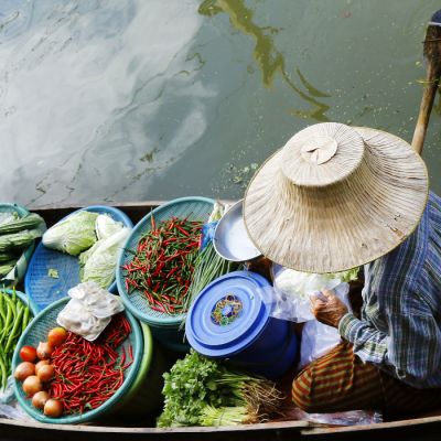 Woman trading fruit and food in boats at Damnoen Saduak floating market ,Thailand