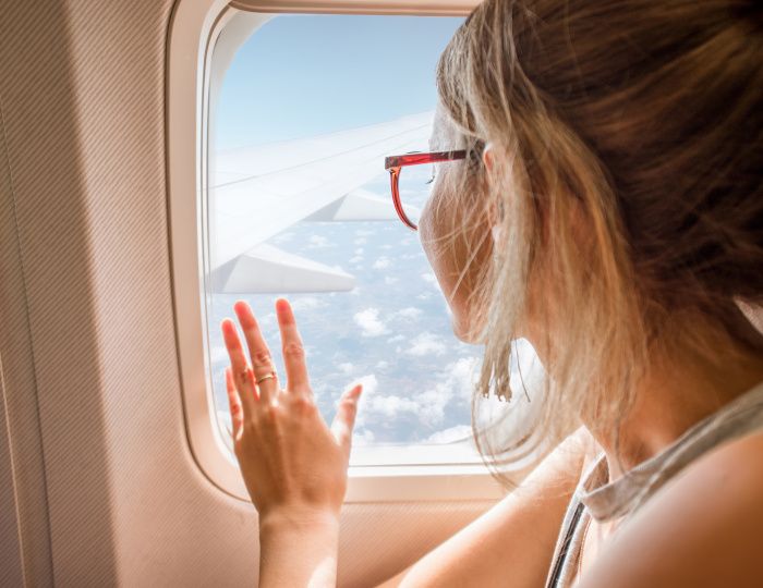 Young woman enjoying the view through the aircraft window sitting during the flight in the airplane
