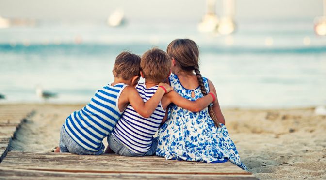 Kinder sitzen am Strand auf Mallorca