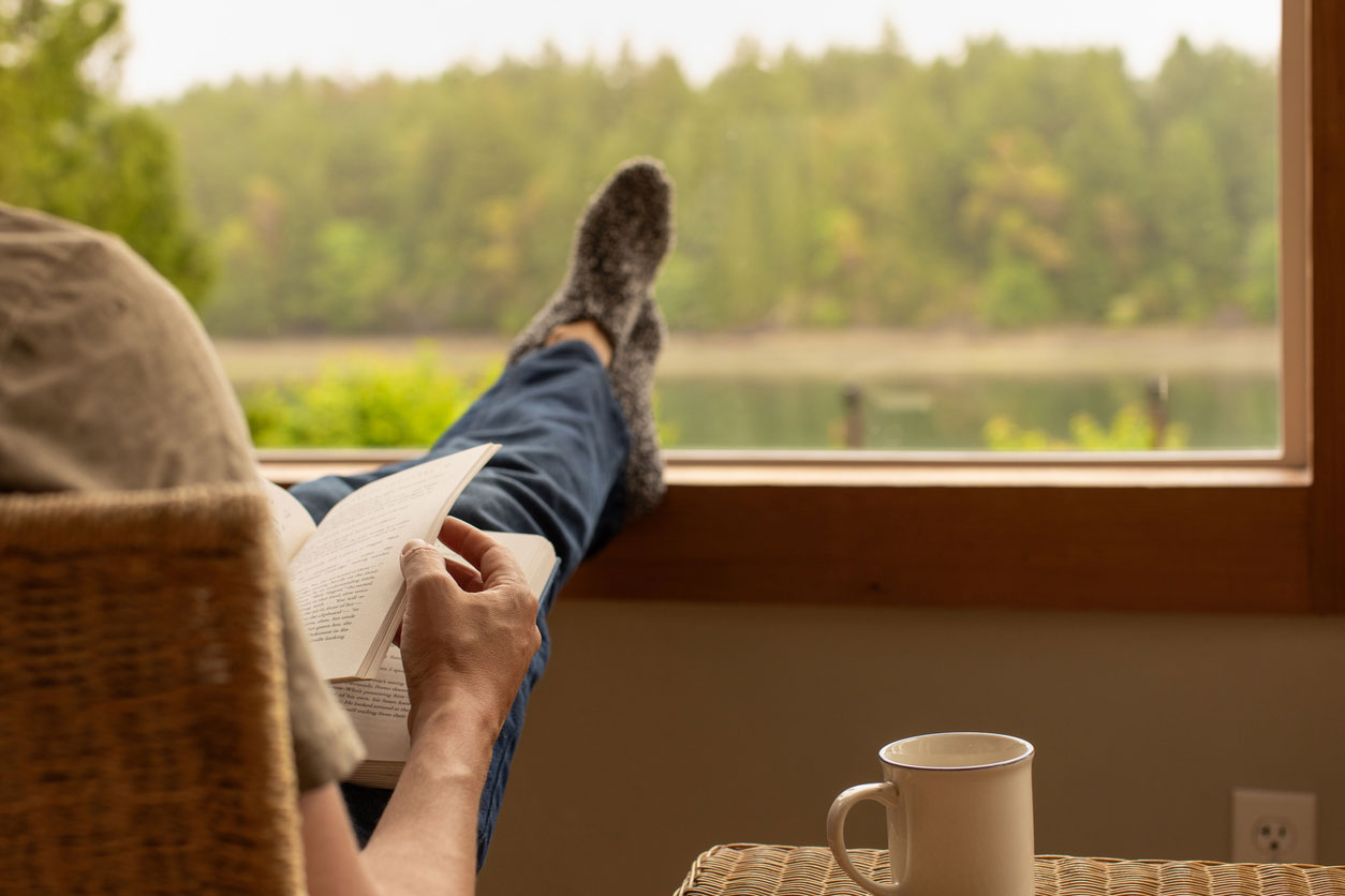 Mann liest ein Buch, daneben steht sein Kaffee.