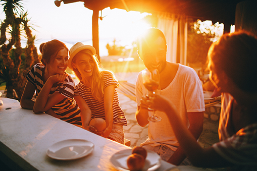 Toasting to our friendship Freunde beim Anstoßen beim Sonnenuntergang in einer Strandbar.