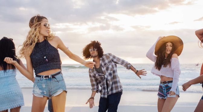 Junge Leute tanzen am Strand.