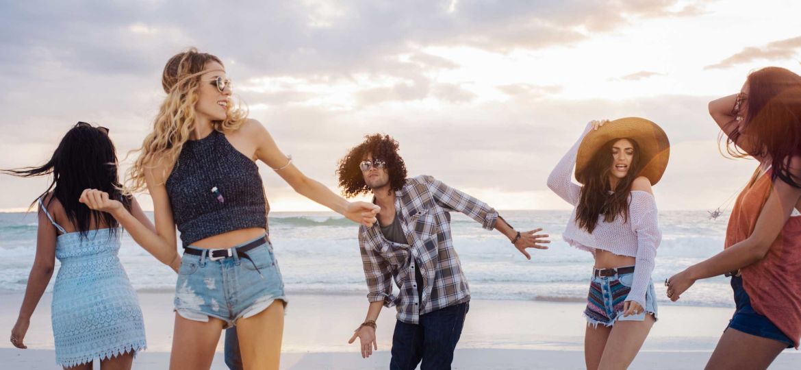 Junge Leute tanzen am Strand.