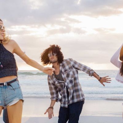 Junge Leute tanzen am Strand.