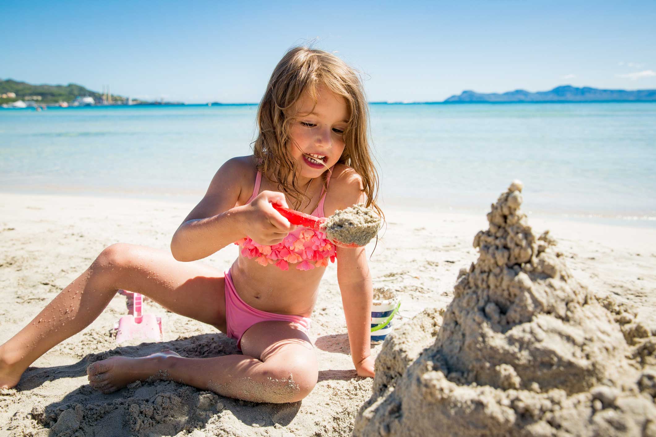 mallorca-kind-am-strand-istock-1034287578 Ein Mädchen spielt mit Sand am Strand von Mallorca.