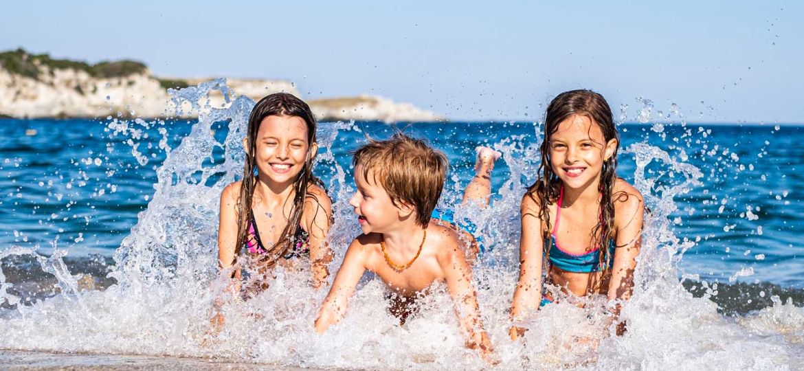 Kinder planschen im Meer.