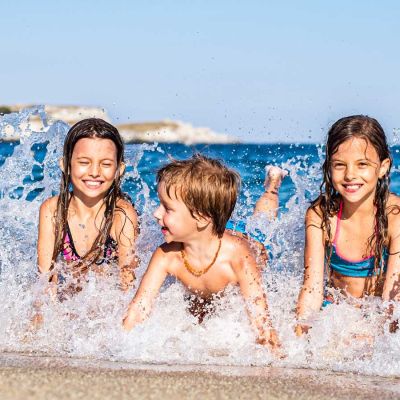 Kinder planschen im Meer.