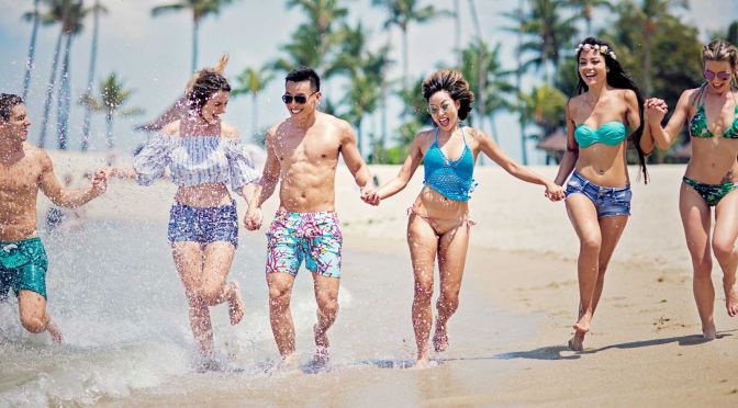Freunde laufen lachend am Strand und haben Spaß.
