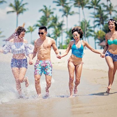 Freunde laufen lachend am Strand und haben Spaß.