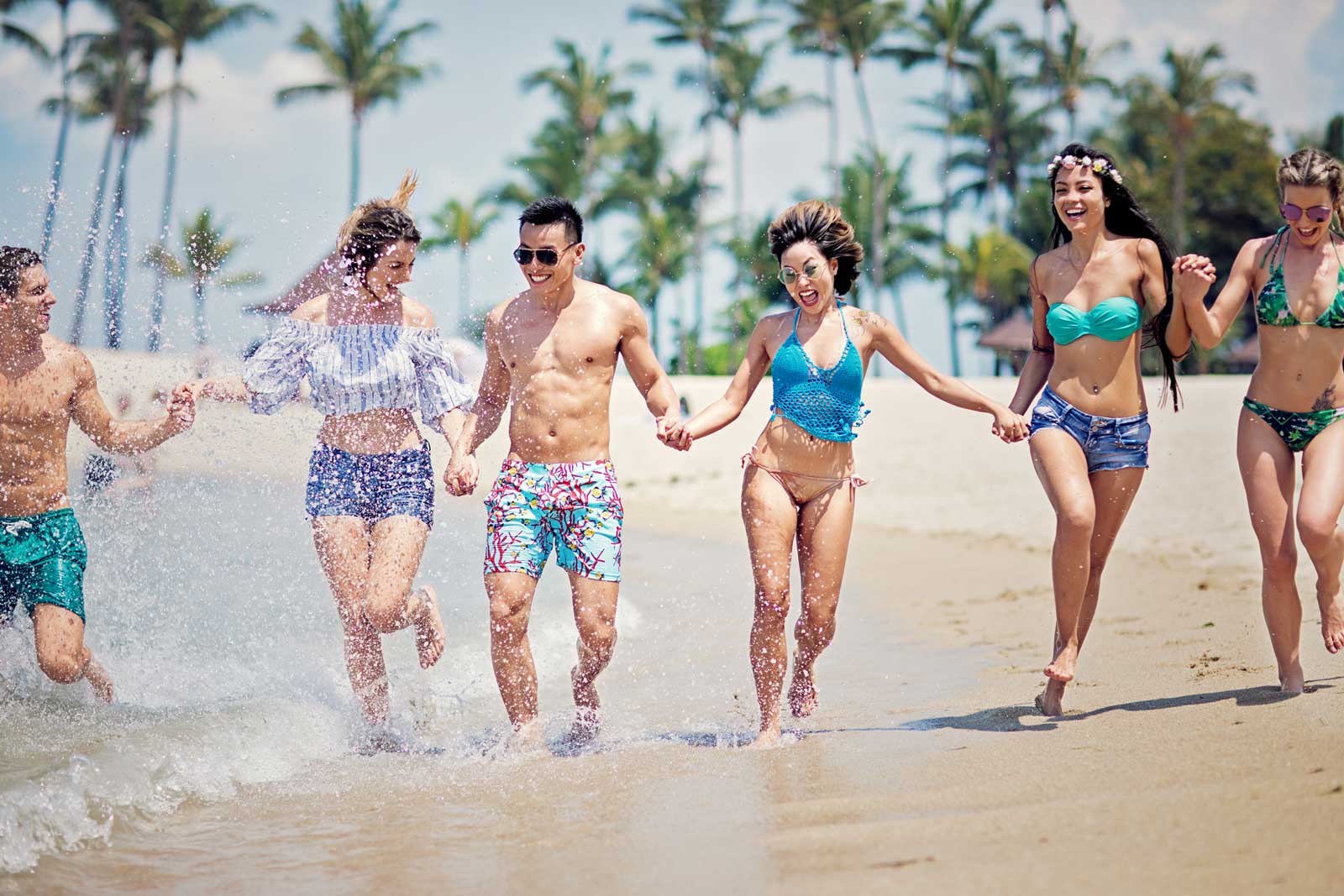 Freunde laufen lachend am Strand und haben Spaß.